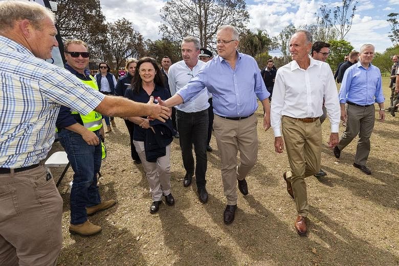 Australian Prime Minister Scott Morrison (centre) greeting members of the local community during a visit to fire-affected Rappville in New South Wales yesterday. Mr Morrison has indicated that he will side with the US in its trade war with China, but