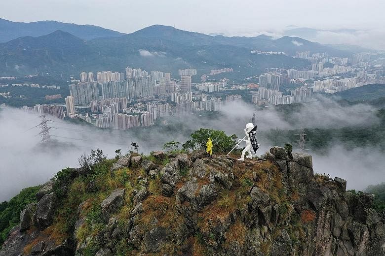 The Lady Liberty statue overlooking the city from up on Lion Rock peak in Hong Kong. The white statue of a protester with a helmet and gas mask was created so that the pro-democracy movement could have its own symbol of democracy instead of borrowing