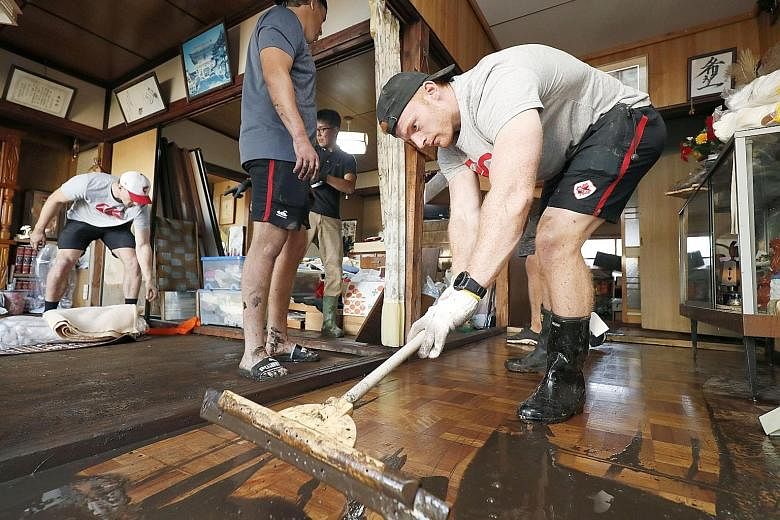 Above: Canada's national rugby union team player Peter Nelson and his teammates, who are in Japan for the Rugby World Cup tournament, helping to remove mud inside a house in a flooded area in Kamaishi, Iwate prefecture, yesterday. PHOTO: REUTERS SEE 