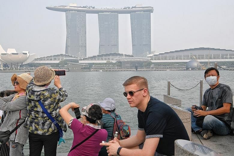 A tourist wearing a mask at the Merlion park on Sept 18. The haze this year was not as bad as the 2015 crisis. In both years, fires were worsened by drier-than-usual weather caused by natural climate phenomena.