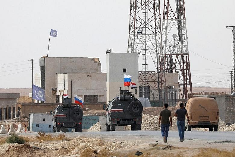 Russian and Syrian flags on military vehicles near Manbij in Syria yesterday. Syrian government forces entered the city, where US troops had previously conducted joint patrols with Turkey. PHOTO: REUTERS Turkish-backed Syrian fighters heading to Kurd