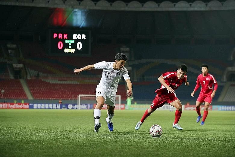 South Korea's Hwang Hee-chan (left) fighting for the ball with North Korea's Kim Chol Bom during their 2022 World Cup qualifier at the Kim Il Sung Stadium in Pyongyang yesterday. The 0-0 draw meant South Korea stayed top of Group H with seven points,