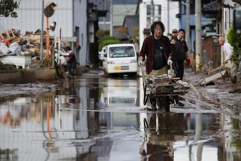 A resident removing muddy items in a flood-hit area in Nagano yesterday. Typhoon Hagibis caused mudslides in 146 places in Japan, while at least 13,000 homes were damaged by flooding. Homes left damaged by the flooding in Nagano, where the embankment