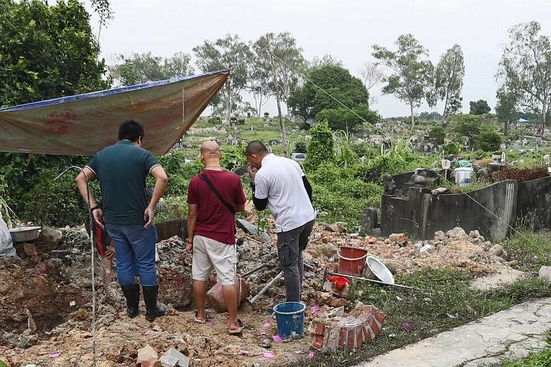 National Environment Agency workers conducting exhumations at Choa Chu Kang Chinese Cemetery. The agency said this is the first time it has encountered this misalignment issue in the 16,800 exhumations conducted as of Sept 30 under Phase 7 of its exh