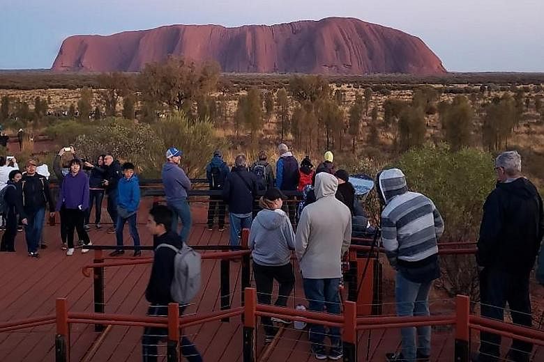 Tourists viewing Uluru in Australia's Northern Territory. Recently, visitors have been rushing to climb the rock, ahead of a ban set to take effect on Oct 26.