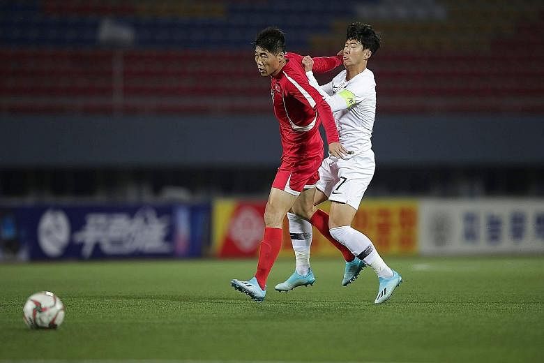 North Korea's Ri Yong Chol holding off South Korea's captain Son Heung-min during a tepid World Cup 2022 qualifier in Pyongyang. The two neighbours played out a goal-less draw in front of an empty stadium without a live broadcast. PHOTO: AGENCE FRANC