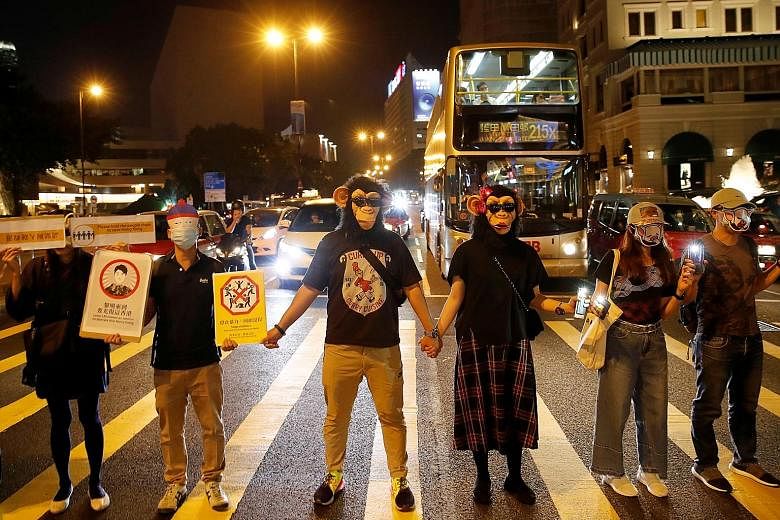 Protesters standing in a human chain which formed across Hong Kong yesterday along the city's metro route, with many wearing masks despite a ban on covering faces at public rallies. In another show of defiance, pro-democracy campaigners are planning 