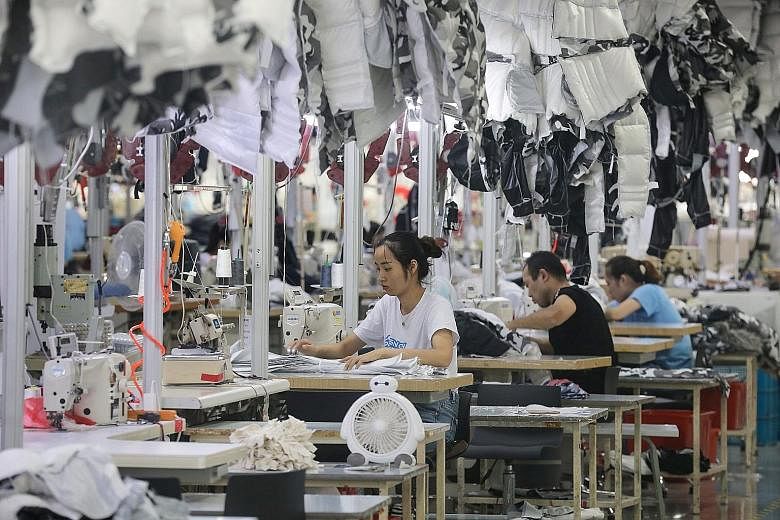 Employees producing down coats at a clothing factory in Nantong, China. China's economic growth has been hit by soft factory production amid a bruising Sino-US trade war. PHOTO: AGENCE FRANCE-PRESSE
