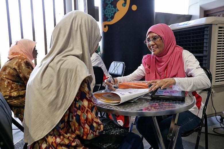 Madam Jamalbi Abdul Hameed (right) attending to a resident at the roadshow in Wisma Geylang Serai yesterday. She has been a Silver Generation ambassador since 2014 and it involves reaching out to seniors at their homes to explain government schemes s