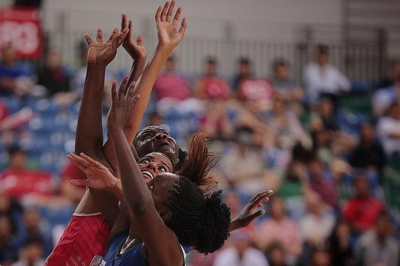 Singapore's Sindhu Nair is sandwiched between two Namibia players as she fights for a rebound in yesterday's M1 Nations Cup netball tournament at the OCBC Arena.