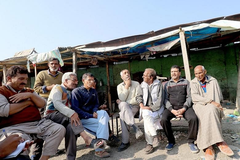 Public bus drivers sitting around the old bus depot in Kashmir's capital Srinagar. They have refused to drive as a mark of protest against the Indian government's decision to revoke the region's seven decades of constitutional autonomy. Dal Lake is c