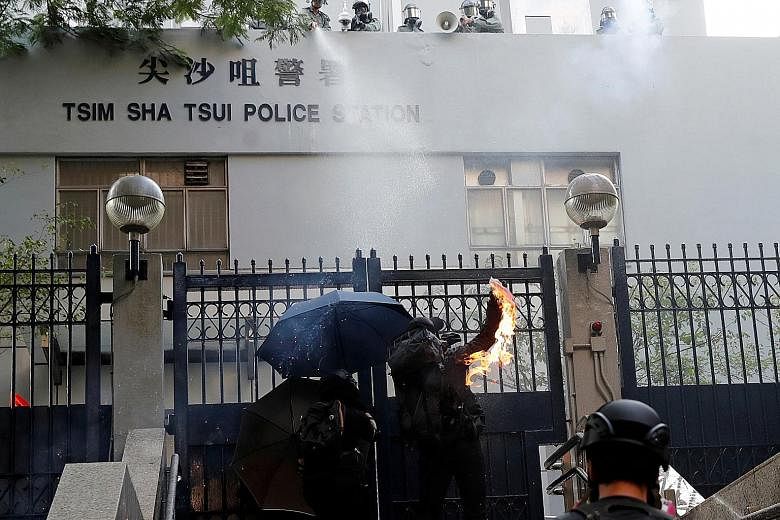 A store that was vandalised on Sunday by protesters. Opinion remains divided on what impact the continuing unrest will have on businesses. PHOTO: REUTERS A protester hurling a petrol bomb into the Tsim Sha Tsui Police Station (left), and another vand
