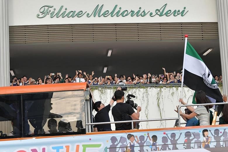 Raffles Girls' School students welcoming a bus carrying RGS principal Poh Mun See (waving flag) and others to the new campus in Braddell Rise yesterday. The RGS project, which has been seven years in the making, cost $90 million and was co-funded by 