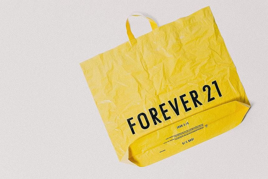 A shopping bag (below) stamped with "John 3:16", a reference to a Bible verse, an example of how the family's Christian faith played a role in their running of the company. Forever 21 founder Chang Do Won with his daughters Linda (far left) and Esthe