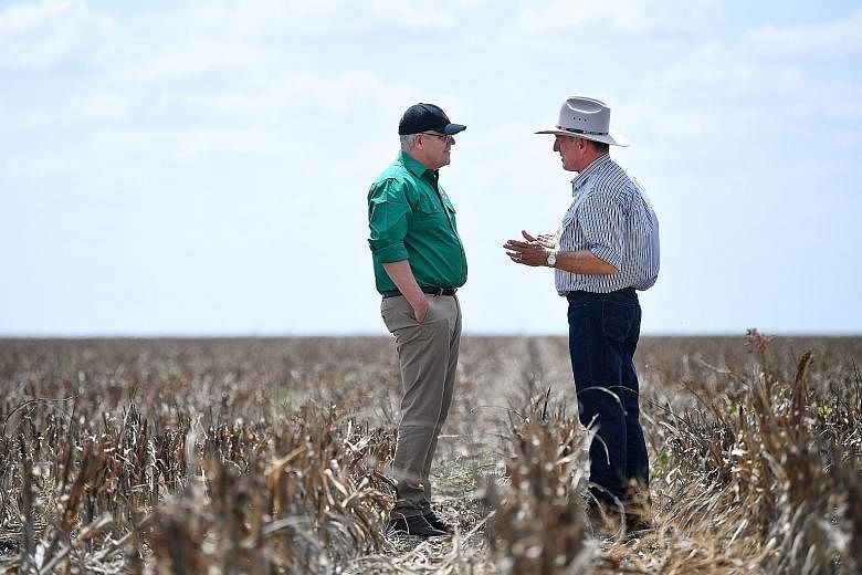 Australian Prime Minister Scott Morrison (left) speaking to a farmer on his drought-affected property near Dalby, Queensland, last month. Mr Morrison's willingness to pray and discuss his faith publicly has helped him to present himself as a straight