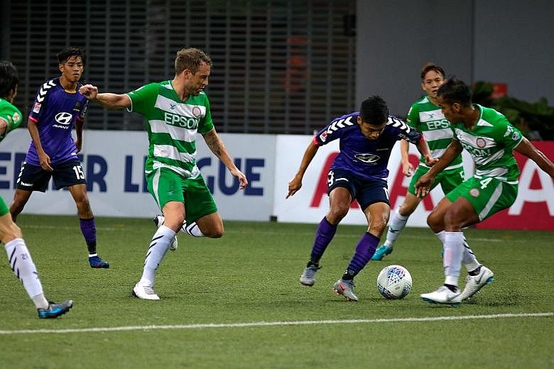Irwan Shah of Tampines maintaining possession of the ball under pressure from Geylang's Barry Maguire (left) and Shahrin Saberin.
