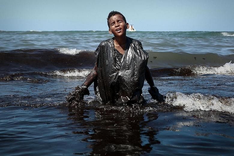 Everton Miguel dos Anjos, 13, seen in a photo taken by an AFP stringer at Itapuama beach in Pernambuco state last Monday. The shot taken as he emerged from the oil pollution spreading along the coast of north-east Brazil for nearly two months went vi