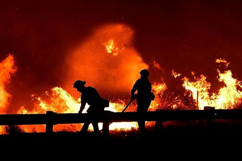 California firefighters battling a fire north of Los Angeles on Friday. Winds gusting at speeds of up 112kmh gave way to light breezes on Thursday, slowing the fires' advance, but the lull was expected to be short-lived.