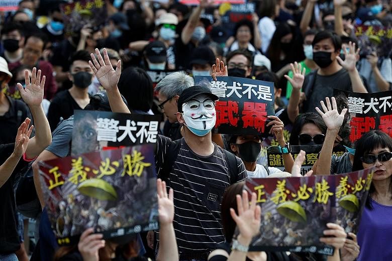 A demonstrator in a Guy Fawkes mask at a rally protesting against alleged police brutality in Hong Kong's Tsim Sha Tsui district yesterday. PHOTO: REUTERS