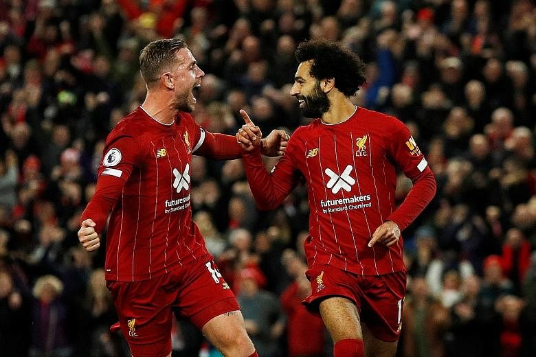 Mohamed Salah celebrating his 50th goal at Anfield with Liverpool skipper Jordan Henderson, who earlier scored the equaliser against Tottenham. The Reds won 2-1 to stay unbeaten. PHOTO: REUTERS