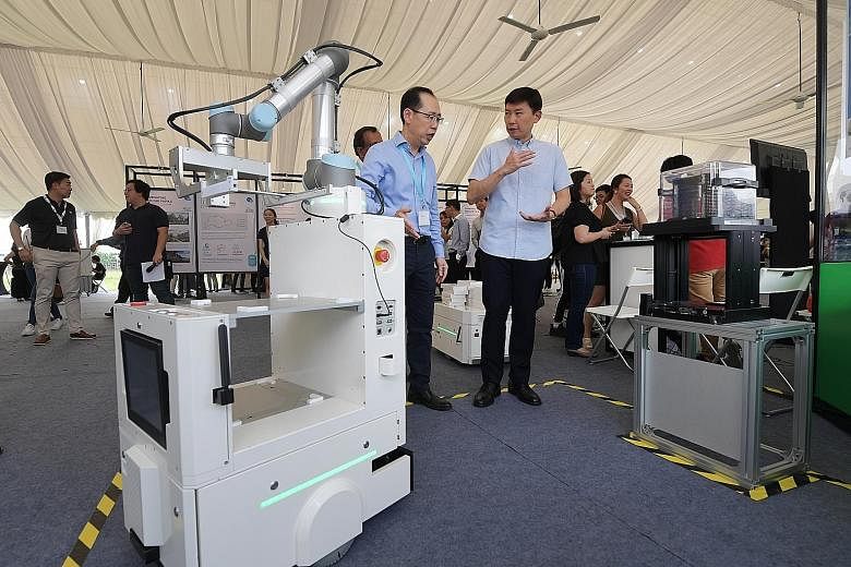 Senior Minister of State for Trade and Industry Chee Hong Tat (at right) being introduced to the Autonomous Mobile Robot by CEI's general manager of equipment manufacturing Joseph Tan at the Electronics Industry Day event at Tampines Wafer Fab Park y