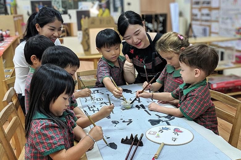 Four-to five-year-olds at EtonHouse Zhong Hua Pre-School being introduced to calligraphy earlier this year by teachers Zhang Yuan Yuan (left) and Huang Ruonan, as part of its Chinese immersion programme. Young children getting early exposure last mon