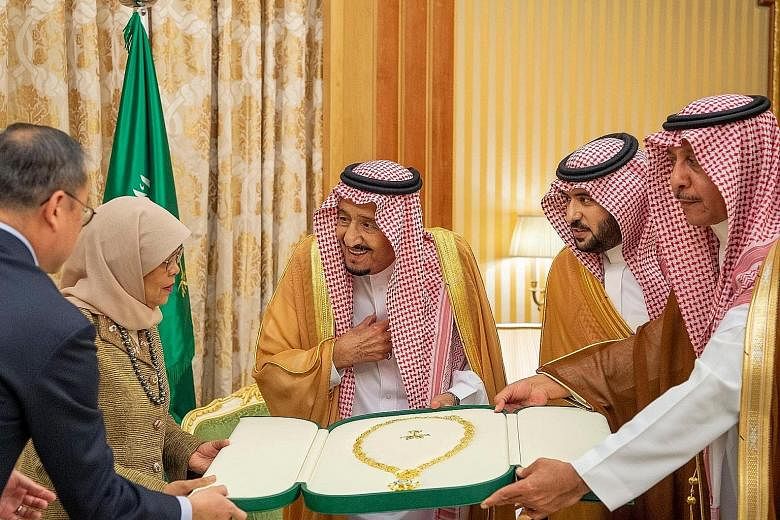President Halimah Yacob receiving the King Abdulaziz Medal from Saudi Arabia's King Salman bin Abdulaziz Al Saud (centre) at the royal palace in the Saudi capital Riyadh yesterday. She is the first Singaporean to receive the award.