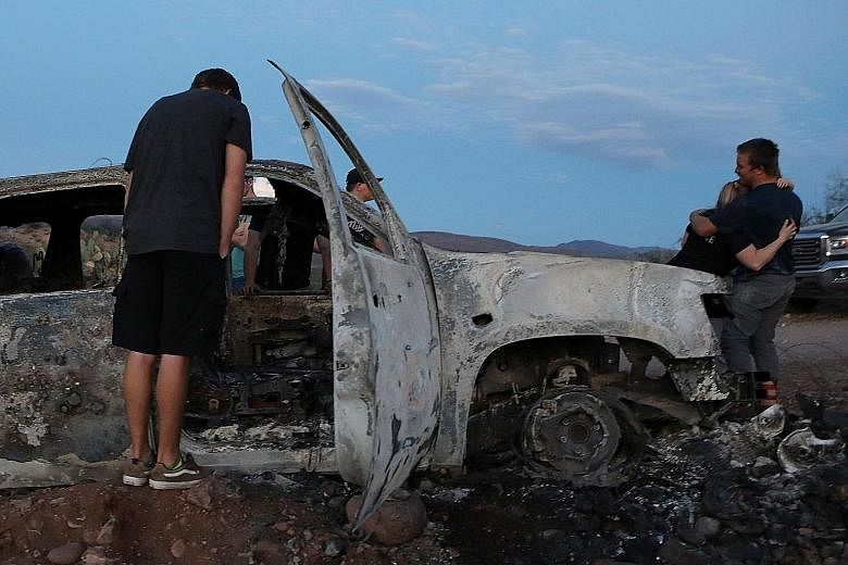 Relatives at a burnt car of the US family who were ambushed in Mexico. At least nine members of the family, including a pair of eight-month-old twins, were killed.