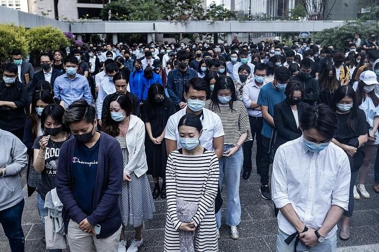 Demonstrators (above) at a protest in Hong Kong yesterday observing a moment of silence for student Chow Tsz Lok, while others laid flowers (left) in tribute at a memorial for the Hong Kong University of Science and Technology undergraduate. PHOTOS: 