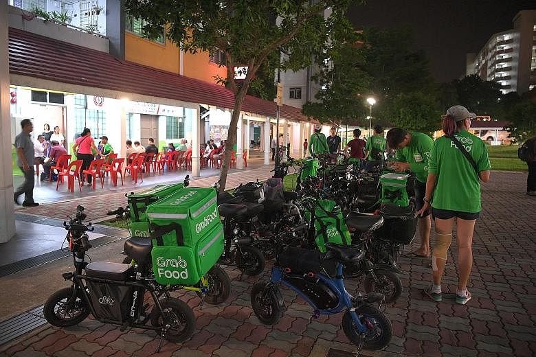Above: Ms Er Y.M., 29, uses her e-scooter for food deliveries, but is uncertain of the future in the wake of the e-scooter footpath ban. Left: A group of food delivery riders in Ang Mo Kio on Thursday. They were there to hand a petition to community 