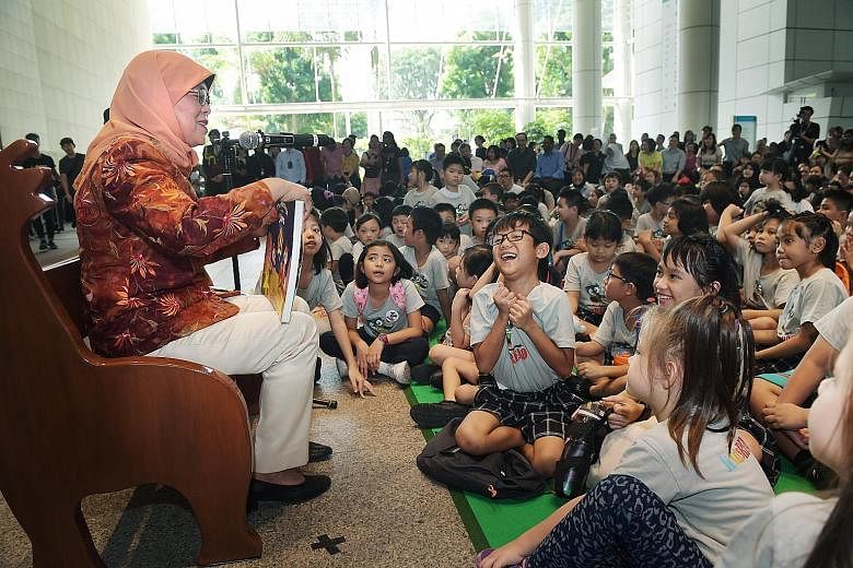 President Halimah Yacob reading a book, The Message In The Stars, to about 230 children, their parents and volunteers at the National Library in Victoria Street yesterday. ST PHOTO: ALPHONSUS CHERN