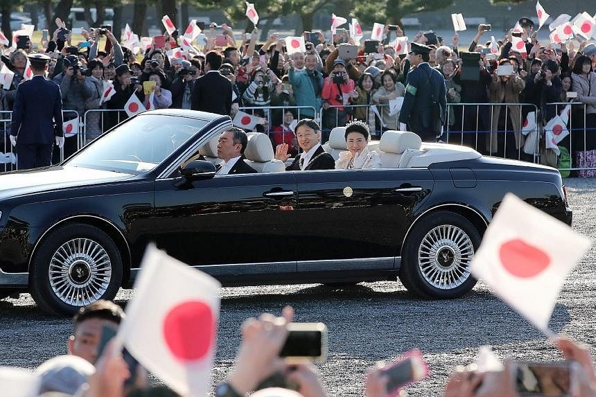 Japan's Emperor Naruhito and Empress Masako waving to the crowd during an open-top car parade in Tokyo yesterday, part of events marking the emperor's enthronement. Tens of thousands of spectators from across the country gathered along the 4.6km rout