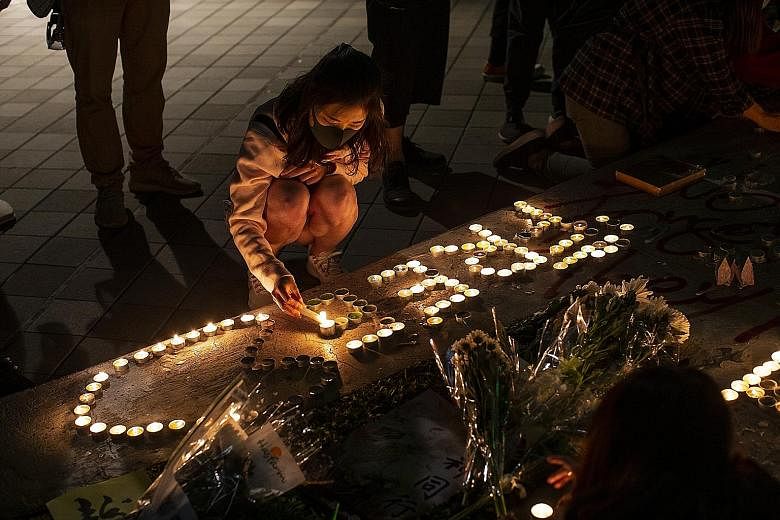 People lighting candles last Saturday to commemorate university student Chow Tsz Lok, 22, who died on Nov 8 after falling one floor from a parking lot during police action to disperse protesters. PHOTO: BLOOMBERG