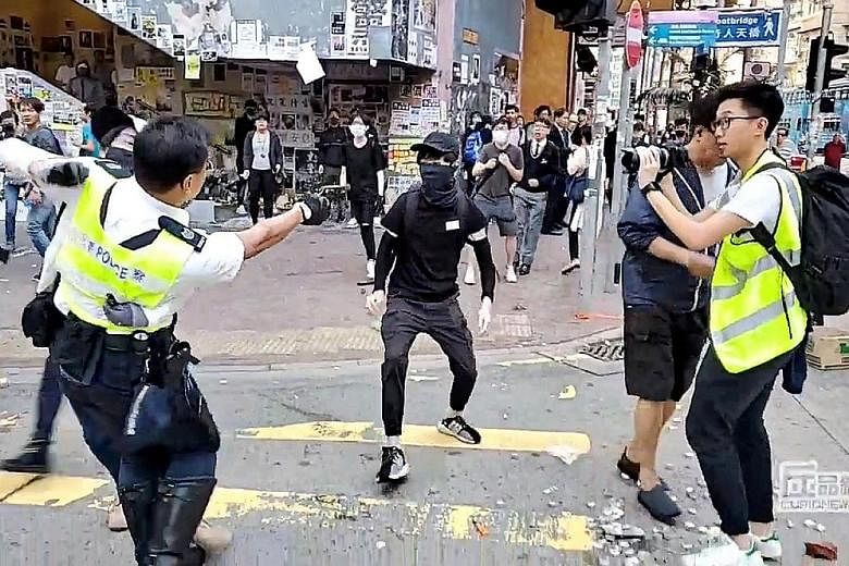 Above: A screengrab showing a man who was set on fire in Ma On Shan during an argument with protesters. Left: A police officer aiming his gun at a protester, before shooting him, in Sai Wan Ho yesterday in a still taken from a video posted online. PH