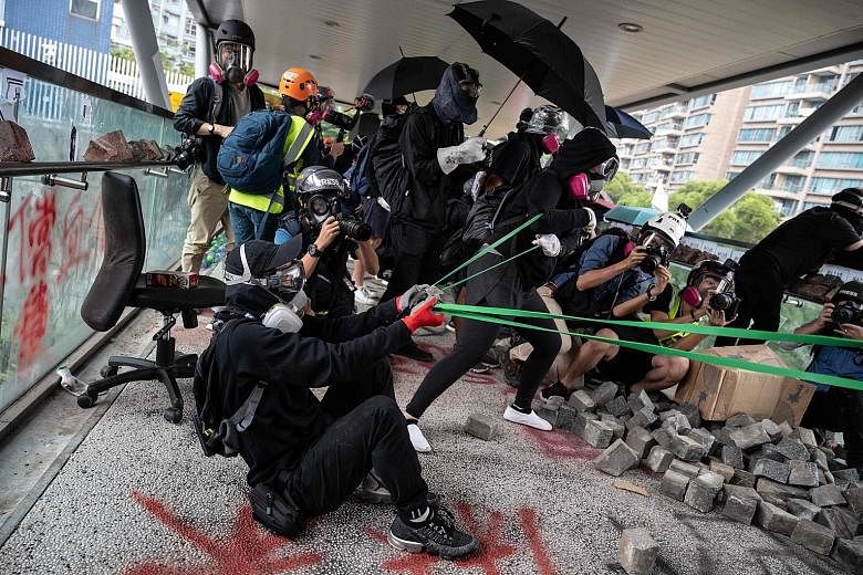 A protester (above) using a catapult against the police at Hong Kong's City University yesterday. The biggest stand-offs took place at the Chinese University of Hong Kong, where pitched battles continued throughout the day. Protests elsewhere disrupt