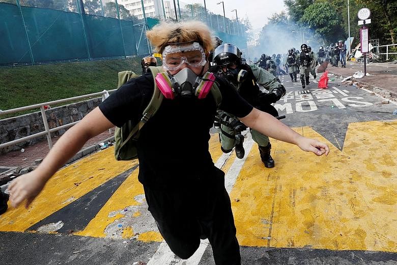 A university student running from riot police at the Chinese University of Hong Kong (CUHK) yesterday. Universities have emerged as a new battleground with sustained clashes at major campuses for the first time. Police fired tear gas at City Universi