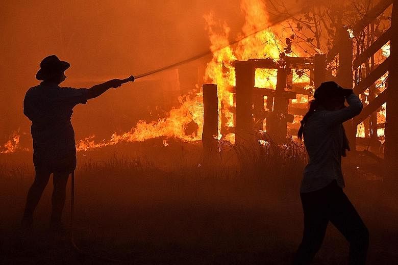 Residents defending a property from a bush fire at Hillsville near Taree, 350km north of Sydney, yesterday. A state of emergency was declared on Monday, and residents in the Sydney area were warned of "catastrophic" fire danger as Australia prepared 