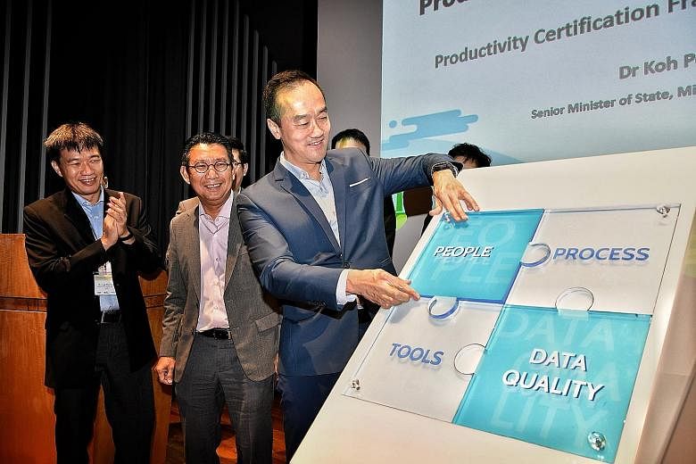 Senior Minister of State for Trade and Industry Koh Poh Koon fixing a piece of a puzzle comprising four areas that firms will be evaluated on, at the launch of the certification framework yesterday. With him at the Trade Association Hub in Jurong Eas