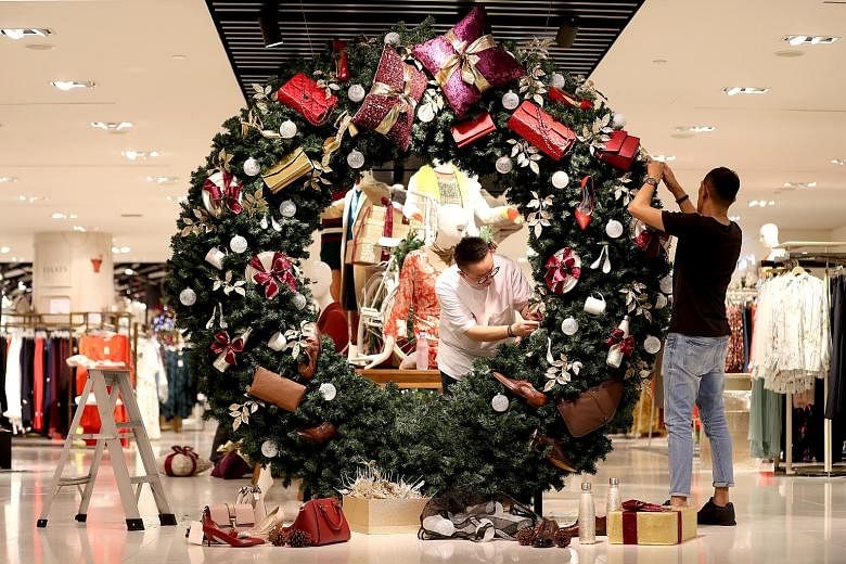 Head of visual merchandising Andre Tan (at left) and visual merchandising executive Arshid Salman from the Robinsons department store adding the finishing touches to their Christmas mistletoe wreath at Raffles City Shopping Centre on Tuesday. The wre