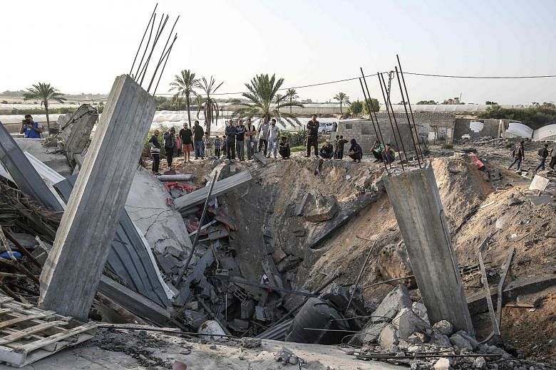 Palestinians gathering around the remains of a house destroyed in an Israeli air strike in Khan Yunis, in the southern Gaza Strip, yesterday. Israel killed Palestinian militant Baha Abu al-Ata and his wife Asma on Tuesday, prompting barrages of rocke