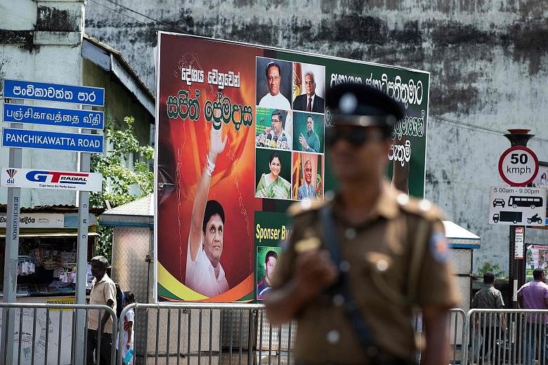 A policeman at a roadblock near a poster featuring presidential candidate Sajith Premadasa (left) in Colombo yesterday. PHOTO: AGENCE FRANCE-PRESSE
