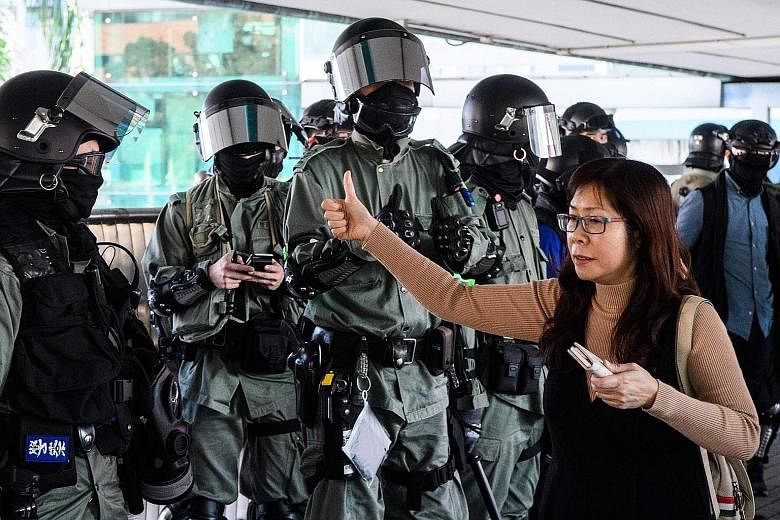 A woman exchanging a thumbs up with a police officer while walking past him on a footbridge in Hong Kong on Monday. A survey in mid-October by The Chinese University of Hong Kong showed some 41.4 per cent of respondents thought the use of radical tac
