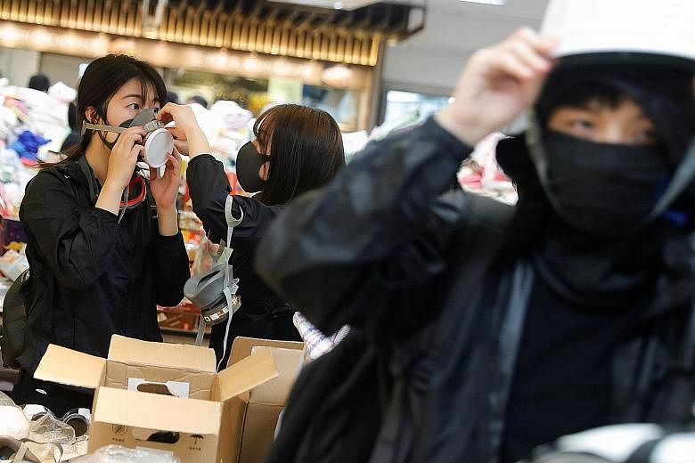 Protesters trying on protective gear (left) and making Molotov cocktails (below) at the Hong Kong Polytechnic University yesterday. Across the city, scenes like these were repeated at nearly half a dozen university campuses. PHOTOS: REUTERS, AGENCE F