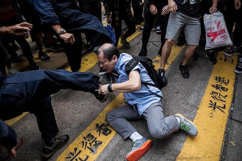 A man being beaten up after getting into an argument during a demonstration of office workers and protesters in Central, in Hong Kong, yesterday. The city's government confirmed yesterday that the police force would get reinforcements from 100 member
