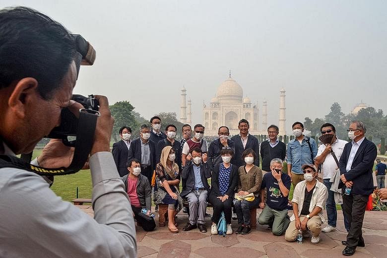 Tourists wearing masks during their visit to the Taj Mahal in India amid heavy smog conditions yesterday. An annual report on the impact of climate change on human health says that people in cities are already suffering premature disease and death fr
