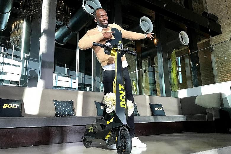 Olympic gold medallist Usain Bolt with an electric scooter at a launch event in Tokyo yesterday. Representatives of his start-up, Bolt Mobility, are encouraging regulators to ease curbs on e-scooters to reduce emissions.