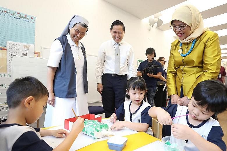 President Halimah Yacob observing a group of children paint, as part of art therapy, at Canossaville Children and Community Services. 