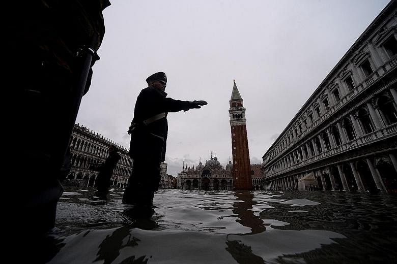 A Carabinieri police officer carrying on with his duties in flooded St Mark's Square in Venice yesterday morning.