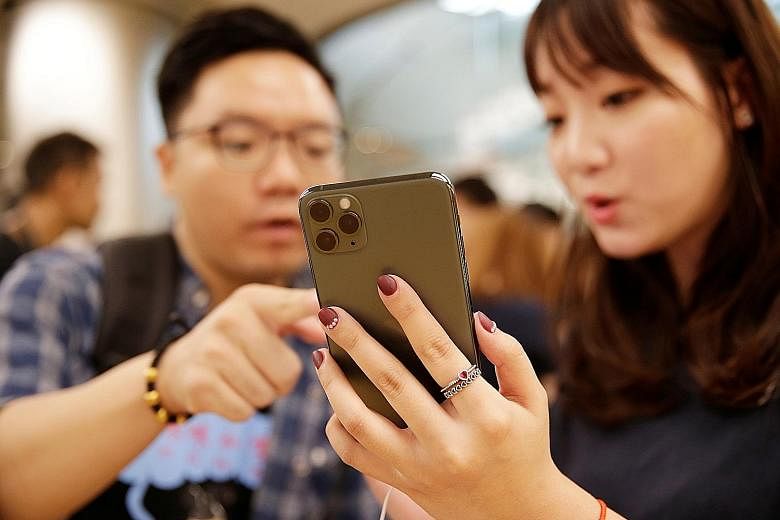 Customers with the iPhone 11 Pro Max at an Apple Store in Beijing. Apple drew positive responses by lowering the starting price of the new devices by US$50 (S$68), and working to increase battery life and overhaul image quality, but it still faces an