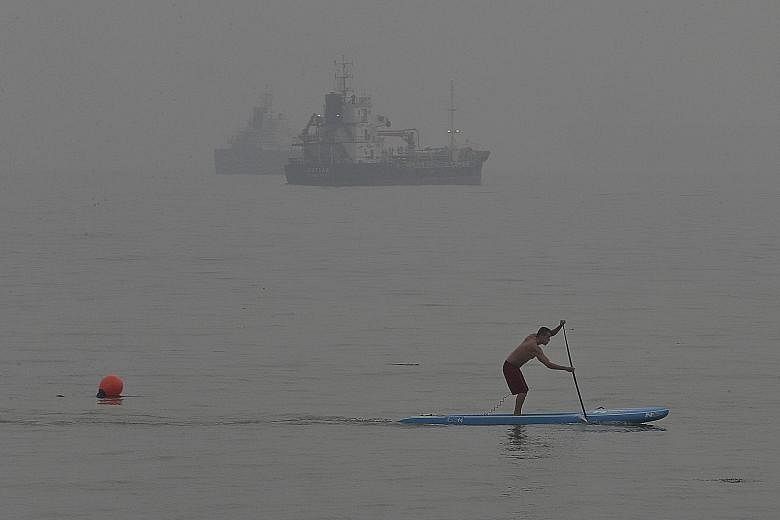 A man, undeterred by the air quality, riding on a paddle board at East Coast Park as the haze partly obscured ships in the distance at around 6pm on Sept 30, 2015.